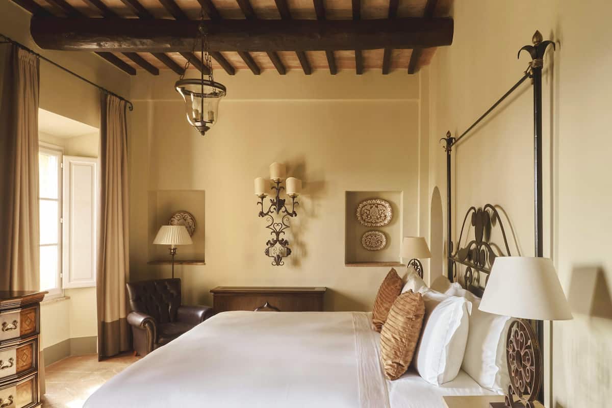 Un dormitorio con una cama grande, una araña, lámparas de pared y platos decorativos.