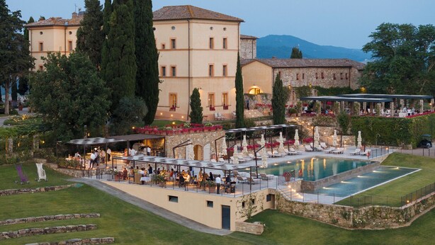 Un hotel con piscina, area relax all'aperto e montagne sullo sfondo.