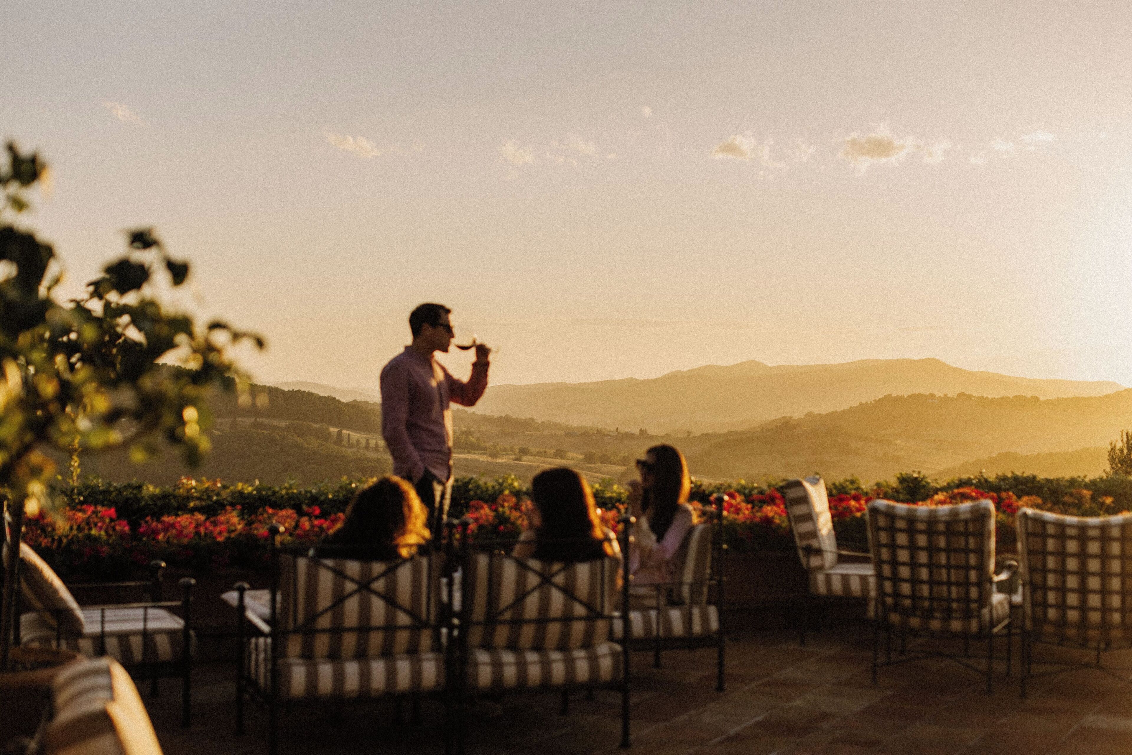 An outdoor seating area with chairs and tables, overlooking a scenic landscape with hills and a clear sky.
