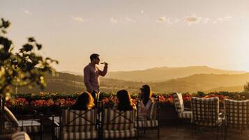 An outdoor seating area with chairs and tables, overlooking a scenic landscape with hills and a clear sky.