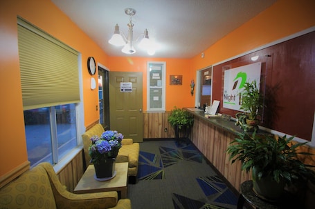 A reception area with a counter, seating, a clock, and a sign for 'The Night'.
