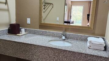A bathroom with a granite countertop, a sink, a mirror, and a towel rack.