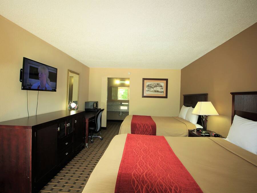 Una habitación de hotel con dos camas, televisión, escritorio y espejo.