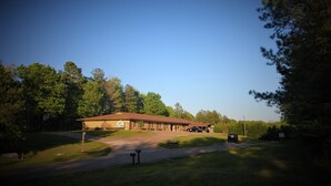 Ein Motel mit eingeschossigem Bau, überdachtem Parkplatz und gepflegtem Rasen.