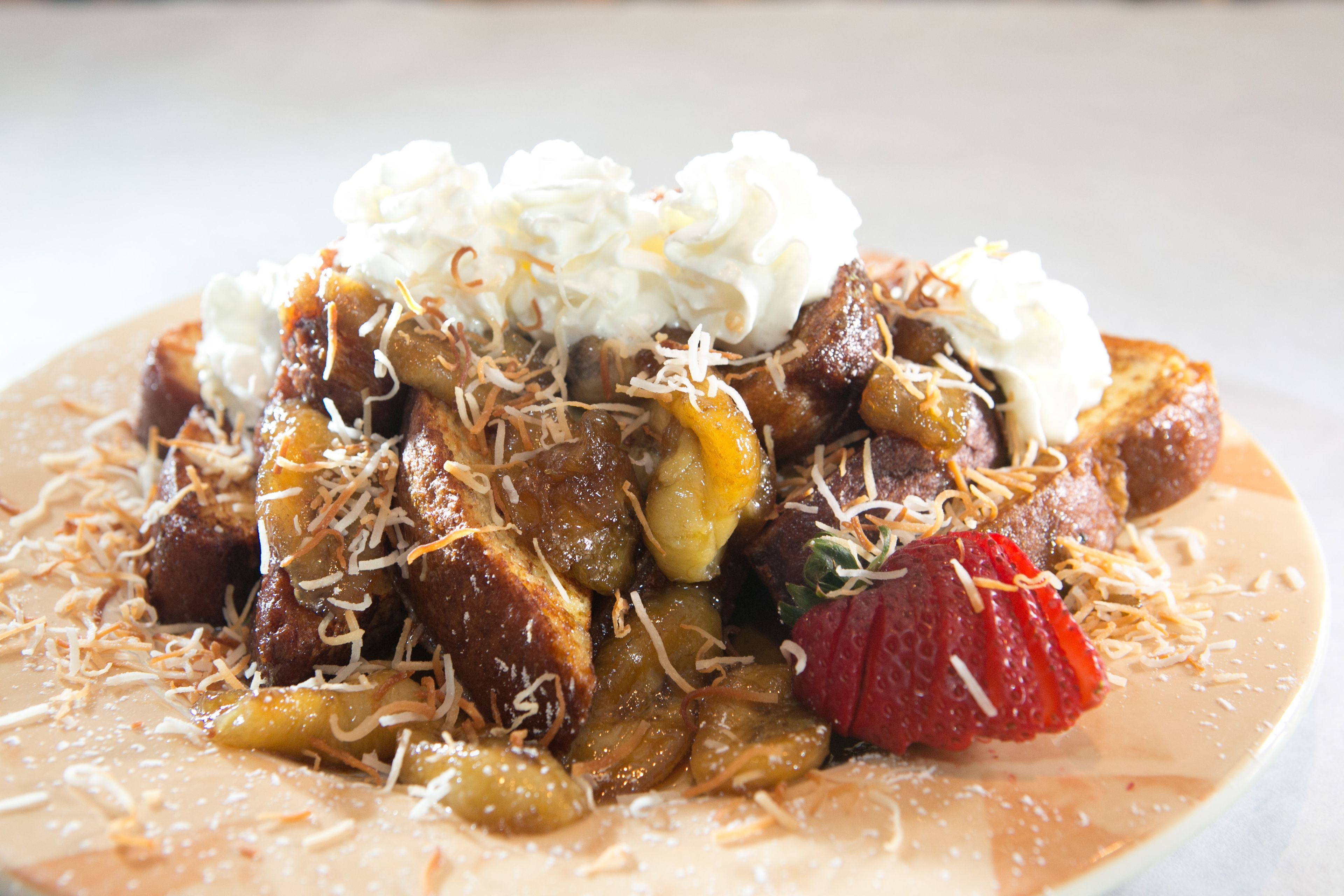 A plate of food with waffles, fruit, and whipped cream.