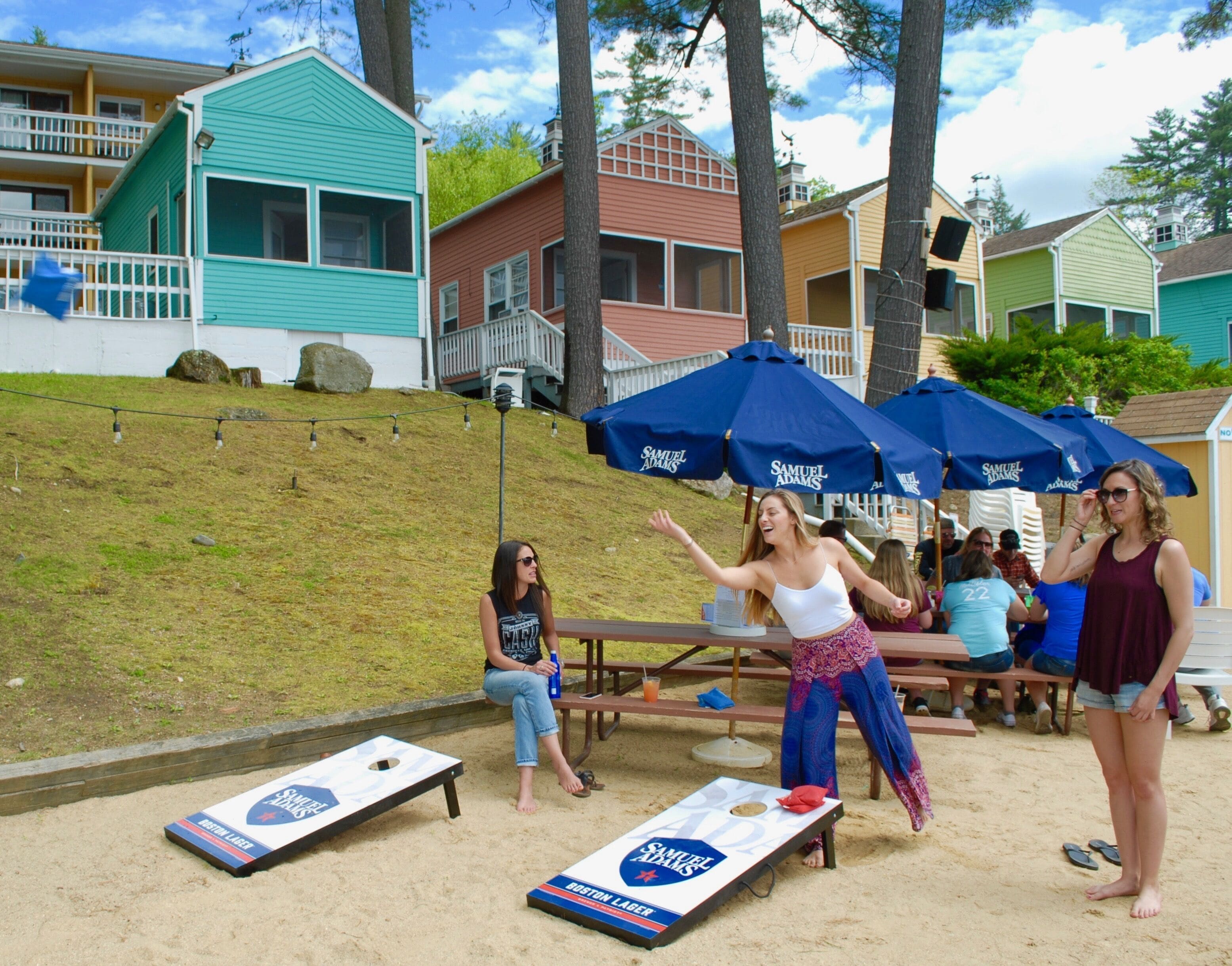 A sandy area with two shuffleboard tables and people playing.