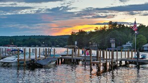 A marina with boats docked, a dock with a sign indicating private docks, and an American flag. - The Naswa Resort (Laconia)