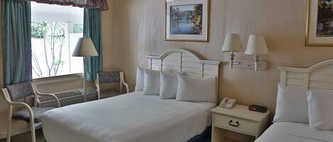 Habitación de hotel con una cama grande, dos mesitas de noche con lámparas, una silla y una ventana con cortinas.