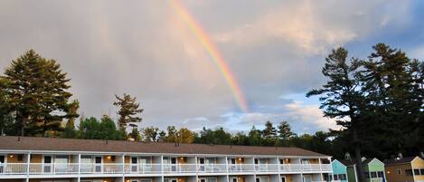 A motel with a poolside area, a rainbow, and a lake.