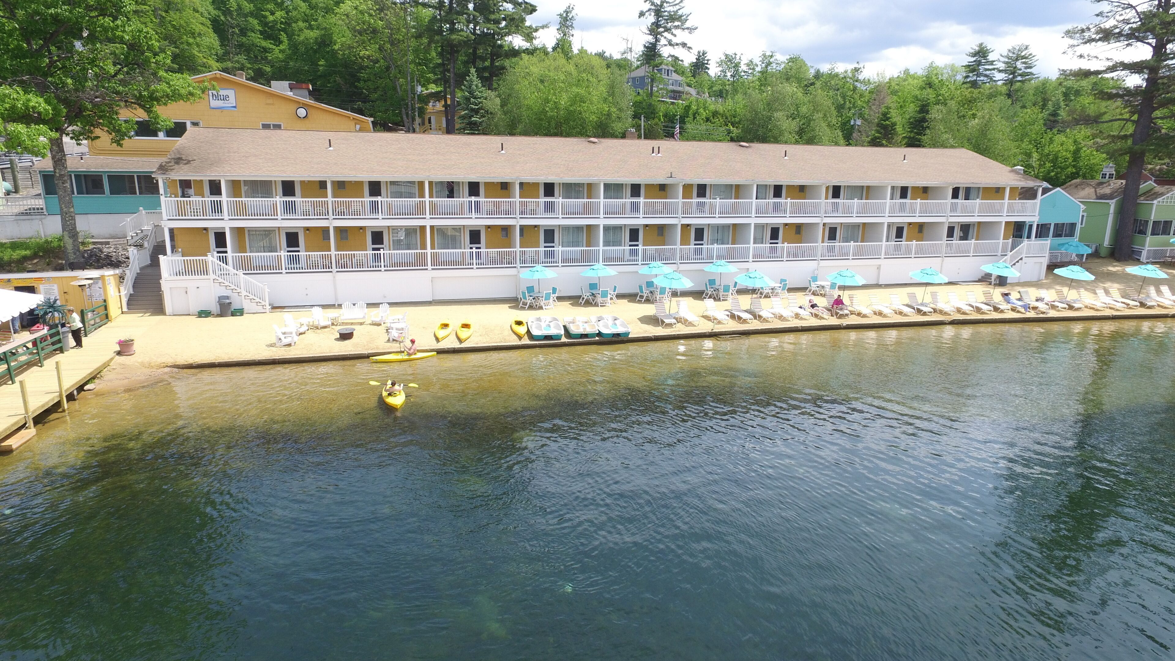 A multi-story hotel with a pool area, kayaks, and lounge chairs.