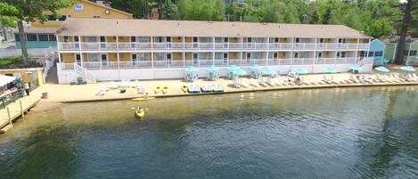 A multi-story hotel with a pool area, kayaks, and lounge chairs.