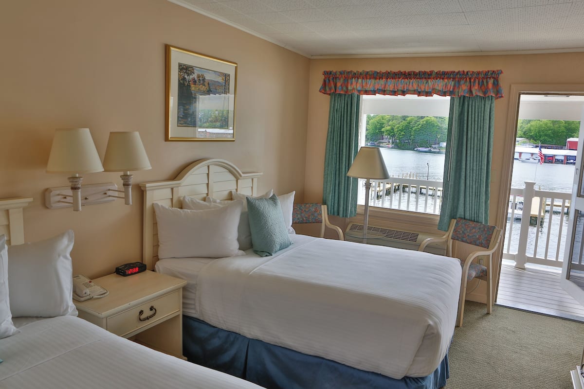 A hotel room with two beds, a desk, and a view of a body of water.