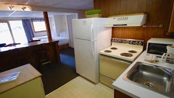 A compact kitchen with a refrigerator, stove, microwave, and sink.