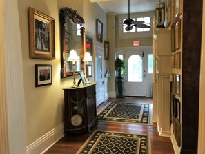 A hallway with framed pictures, a grandfather clock, and a door with an 'EXIT' sign.