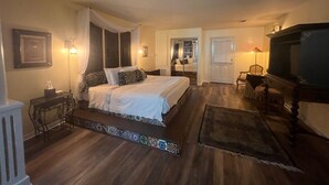 Une chambre avec un grand lit, des tables de chevet, une télévision et un miroir.