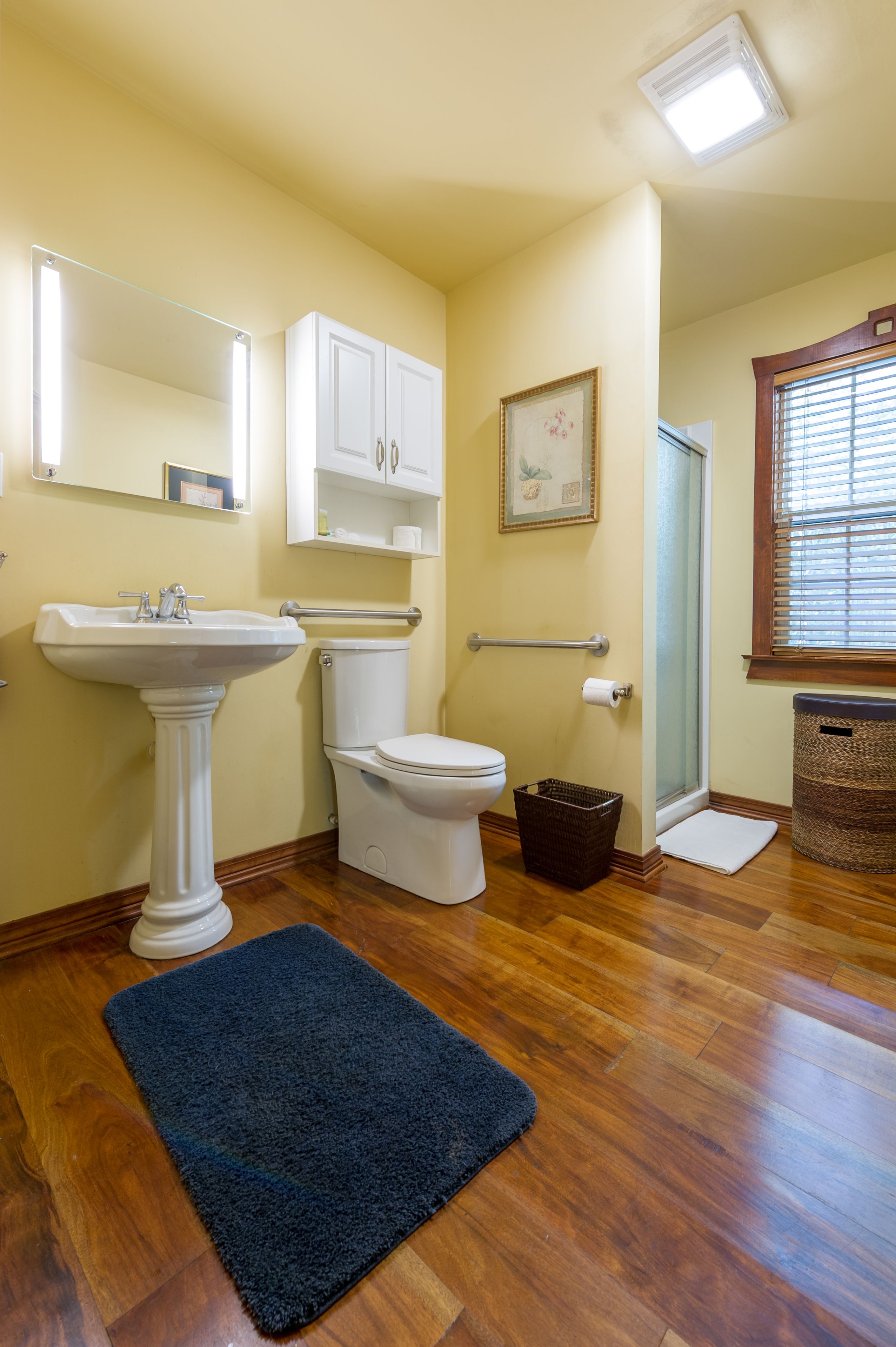Un baño con lavamanos pedestal, inodoro y zona de ducha.