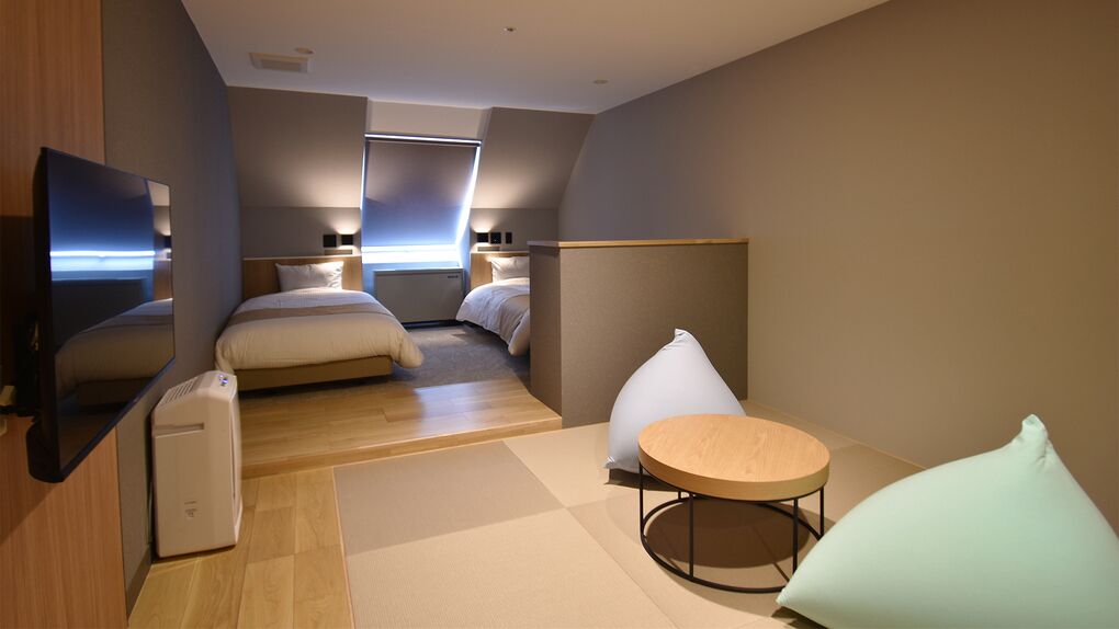 Een moderne hotelkamer met een bed, een televisie, een klein tafeltje en een zithoek.