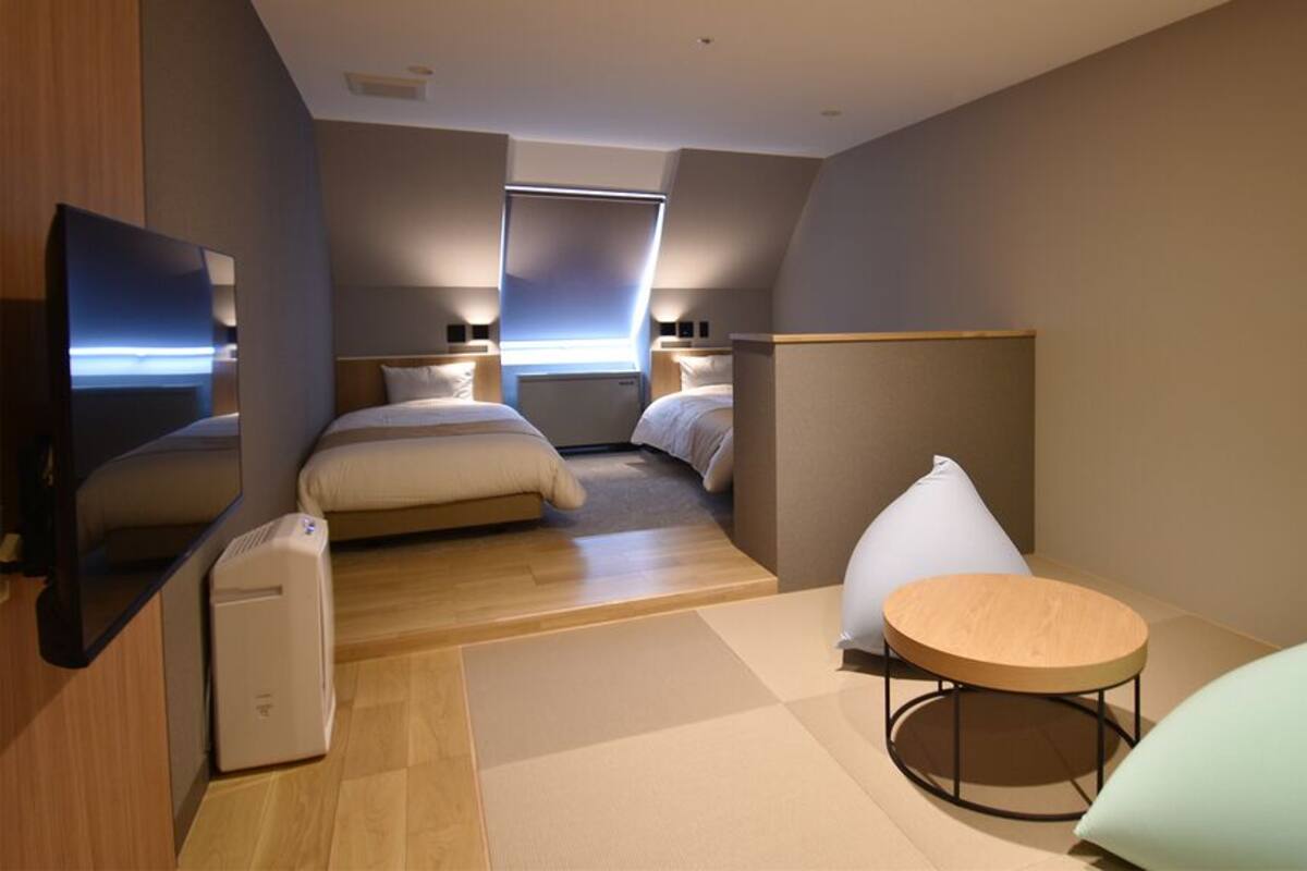 Una habitación de hotel moderna con cama, televisor, una mesita y zona de estar.