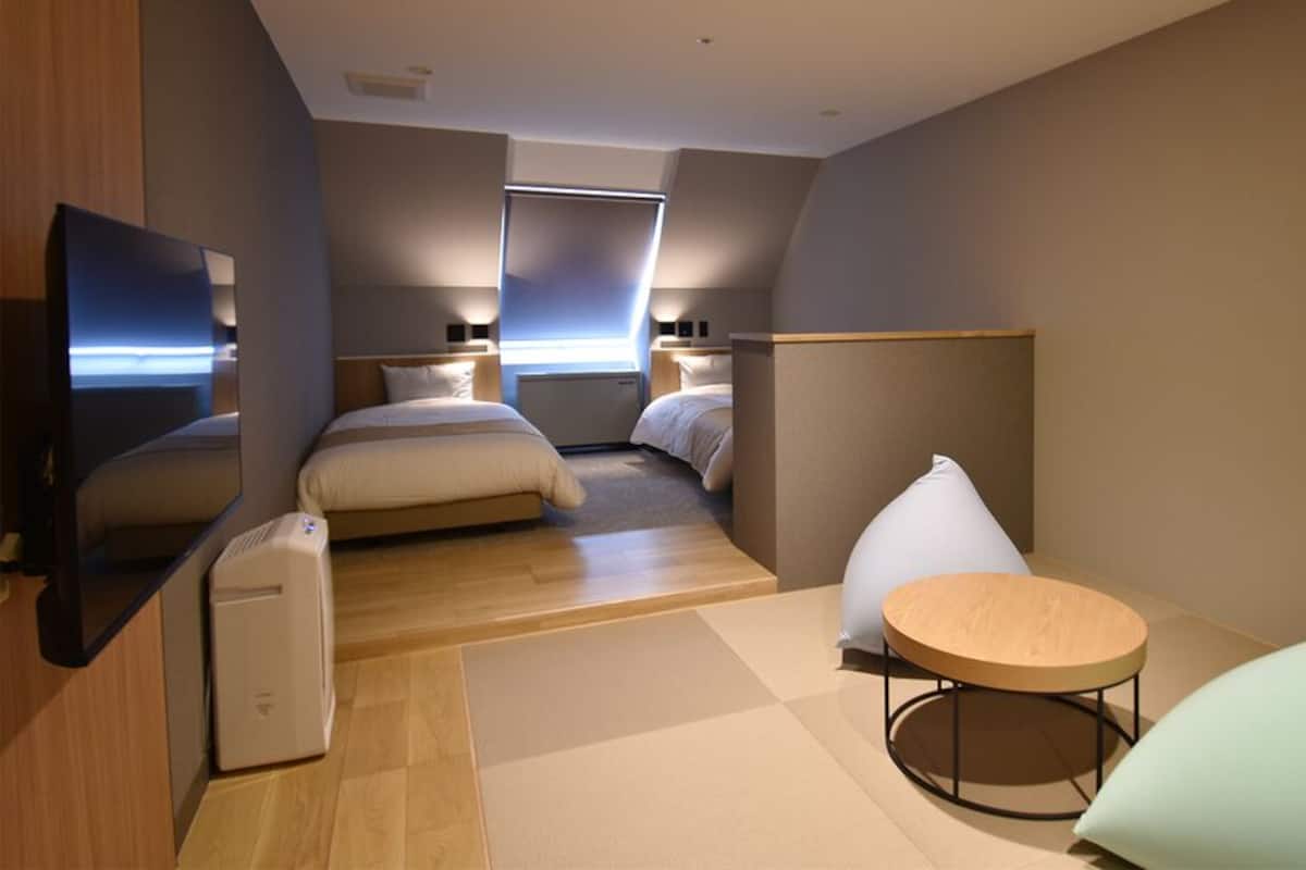 Una habitación de hotel moderna con cama, televisor, una mesita y zona de estar.