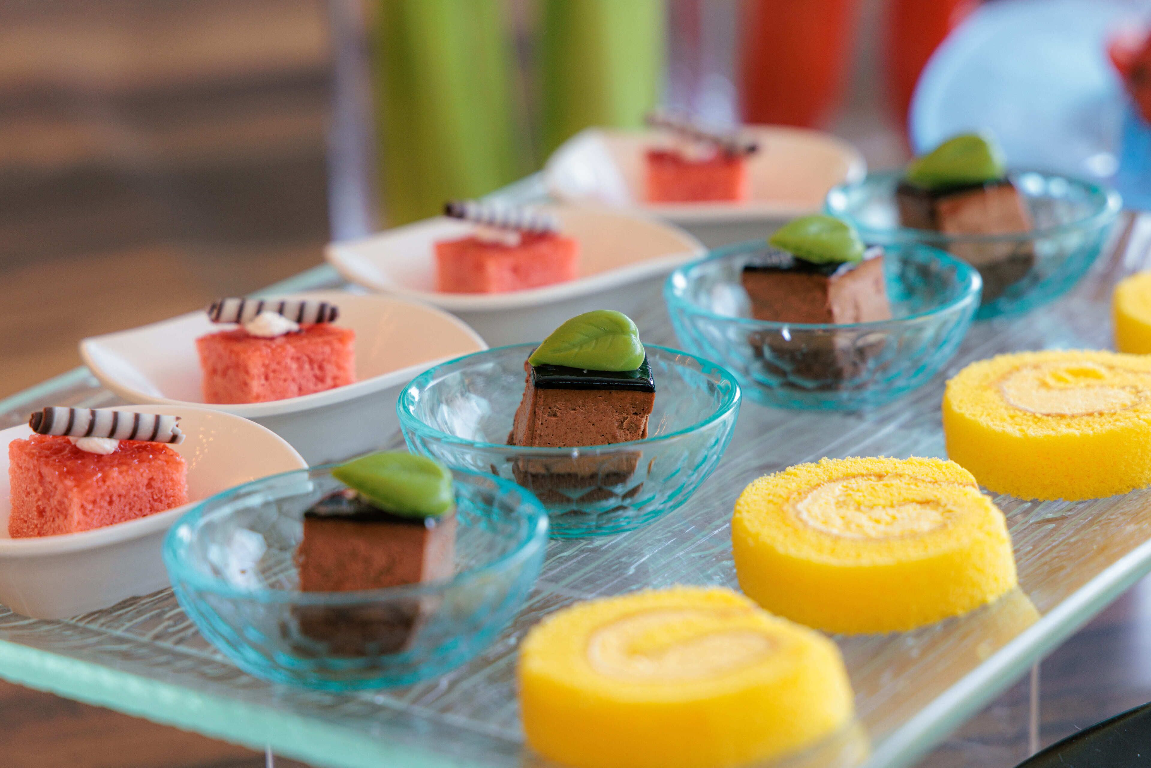 A variety of desserts on a glass tray, including cakes and a roll.