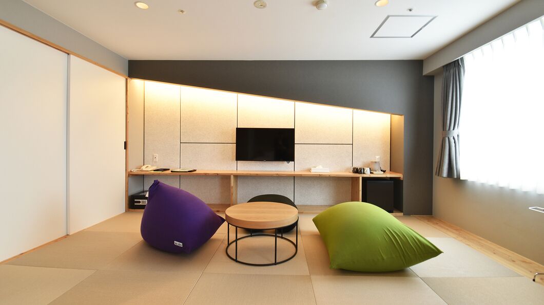 Een moderne kamer met een flatscreen televisie, een ronde tafel en twee loungestoelen.