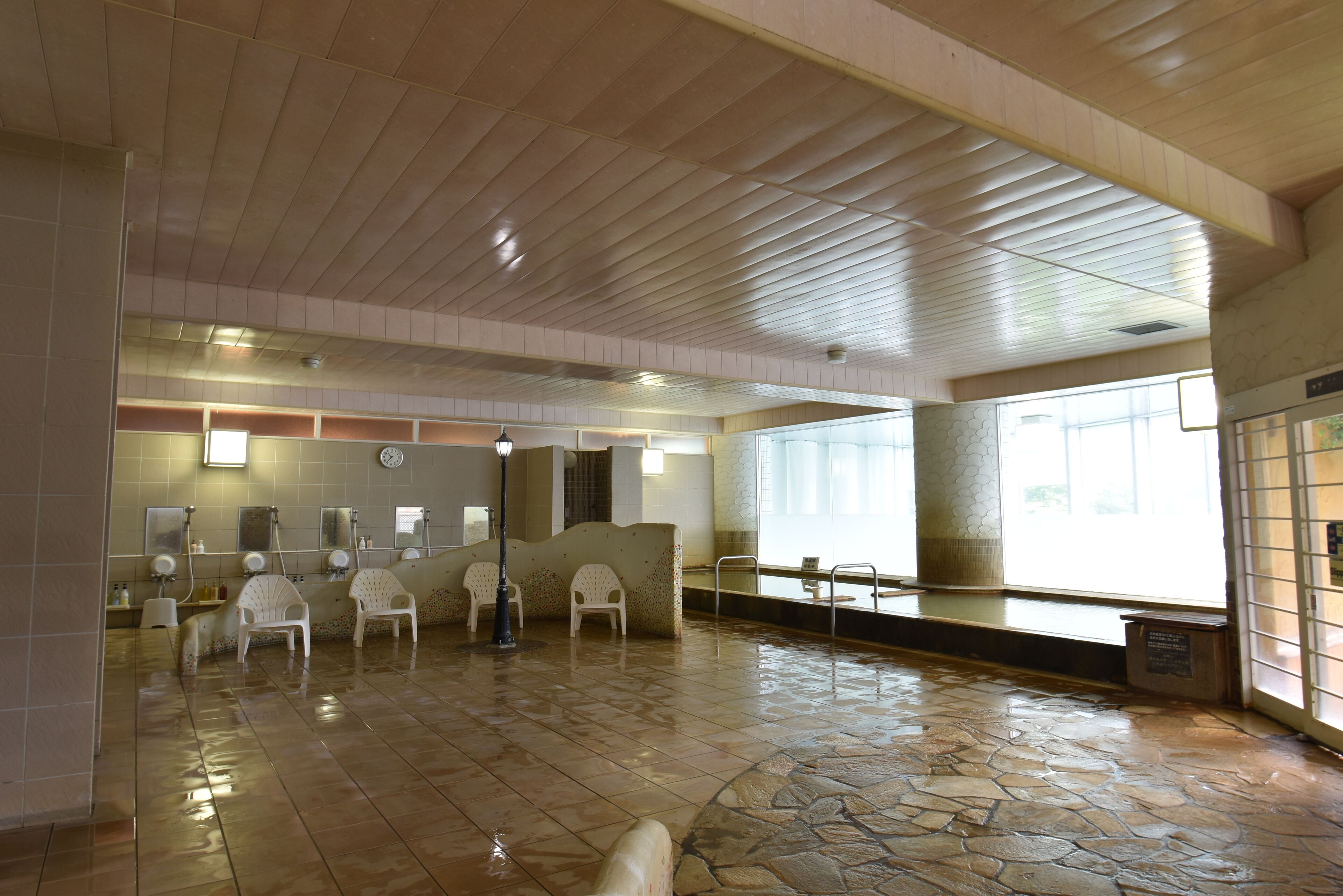 A spacious lobby with a stone floor, a reception area with a counter and chairs, and large windows allowing natural light.