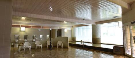 A spacious lobby with a stone floor, a reception area with a counter and chairs, and large windows allowing natural light.