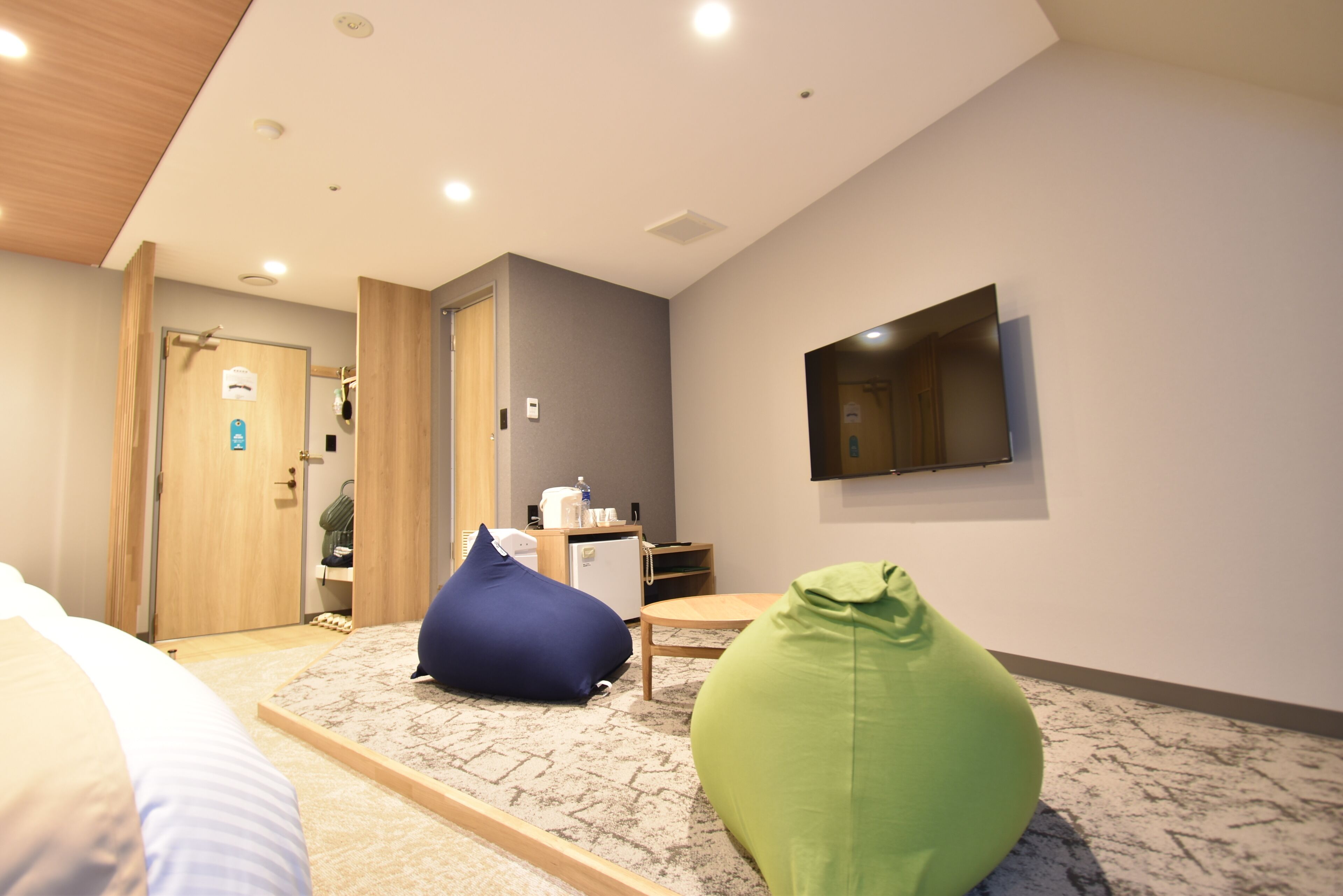 A hotel room with a bed, a desk, a chair, a television, and a door leading to a bathroom.