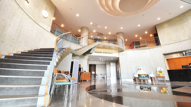 Un vestíbulo amplio con una escalera central, una recepción y un diseño de techo moderno.