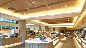 Un amplio vestíbulo de hotel con una isla central que ofrece un bufé, paneles de madera y un techo alto con iluminación empotrada.