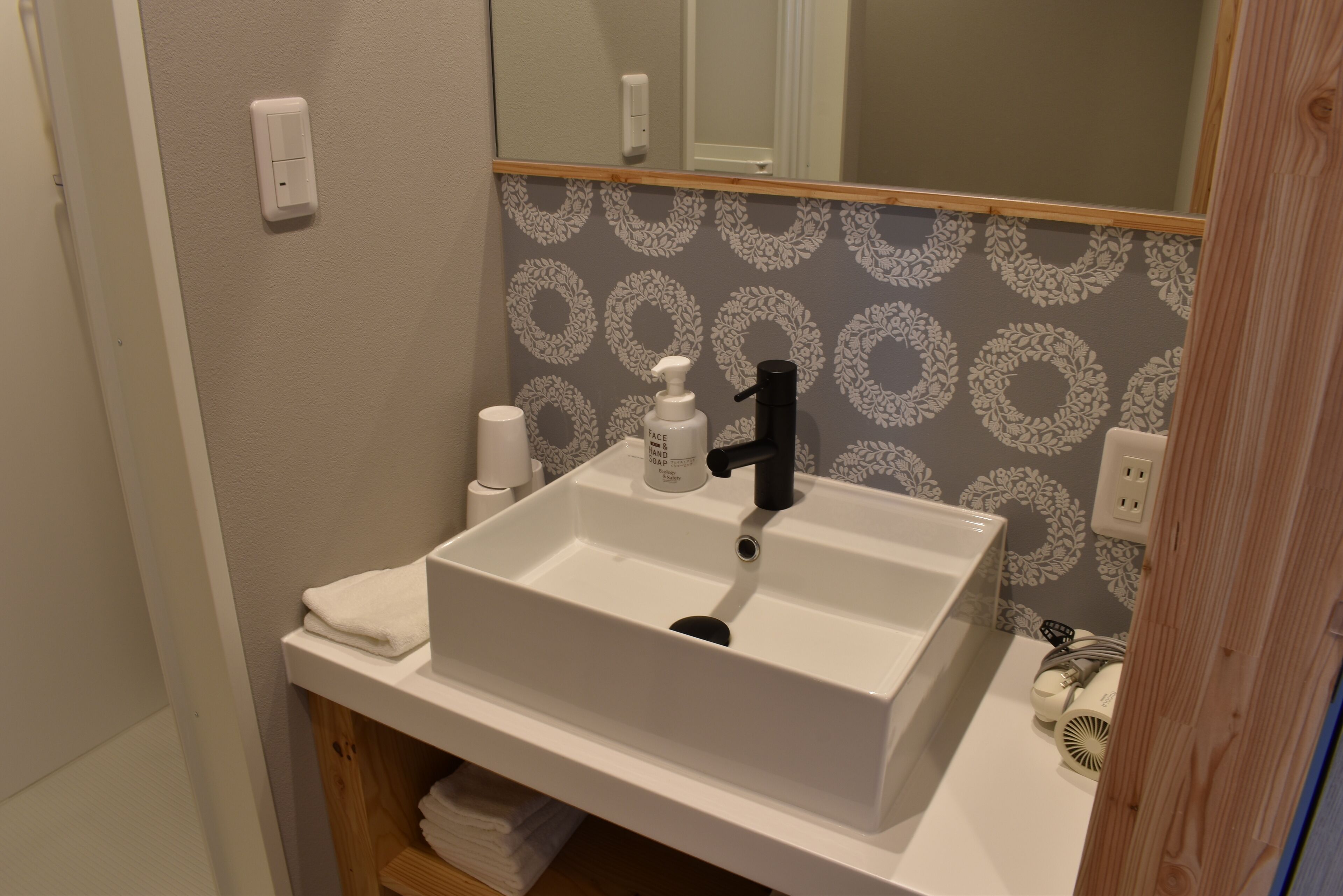 A bathroom with a white sink, a mirror, and a towel rack.