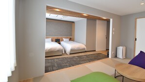 Habitación de hotel con dos camas, una mesita, una silla y un cubo de basura visible.