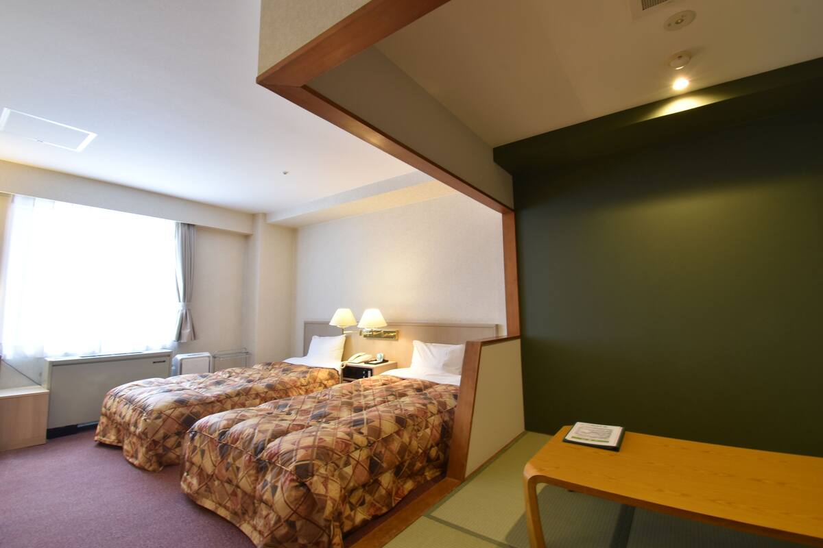 Una habitación de hotel con dos camas, un escritorio, una silla y una mesita.