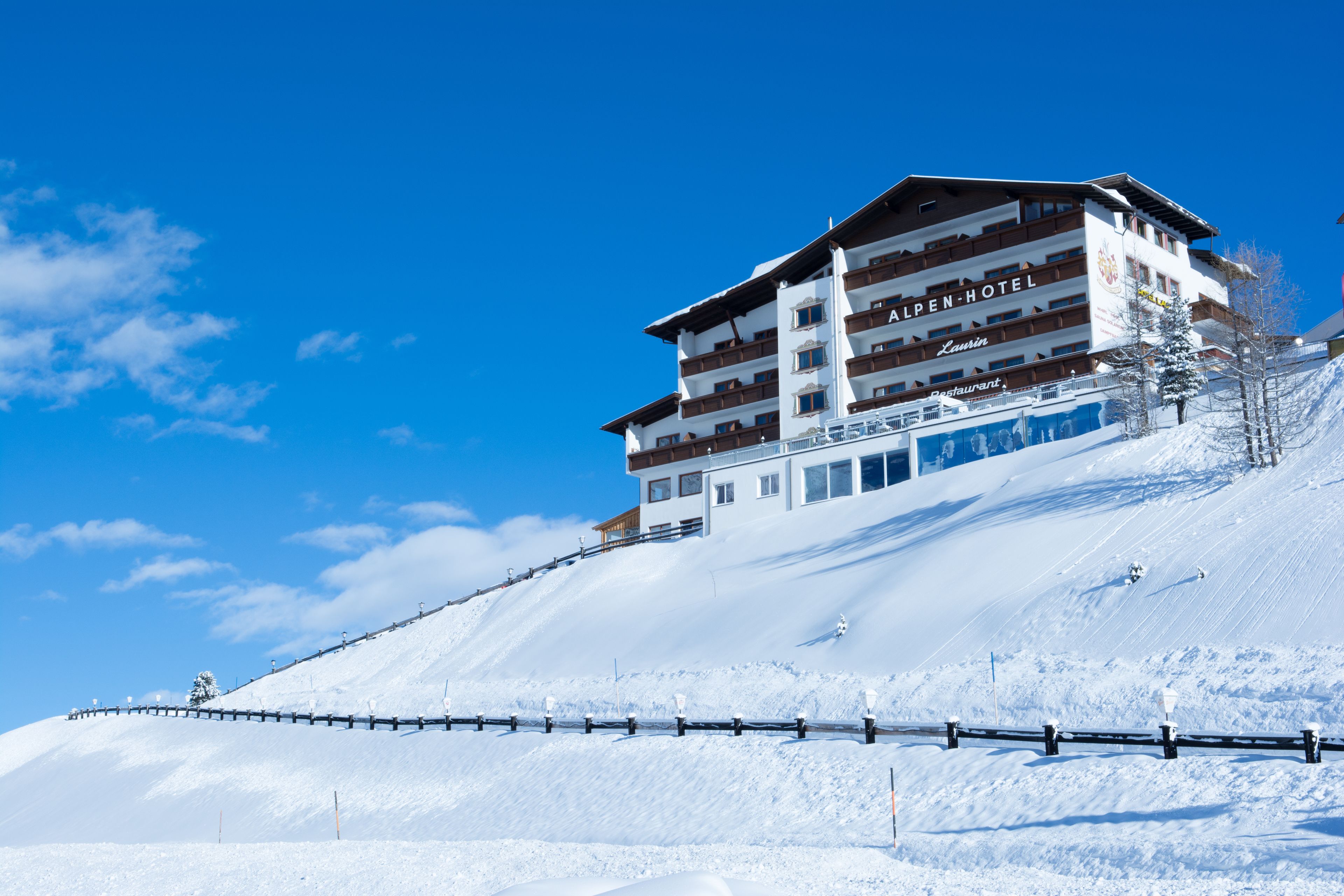 Un hotel de varios pisos con una pista de esquí al fondo.