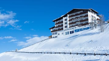Un hotel de varios pisos con una pista de esquí al fondo.