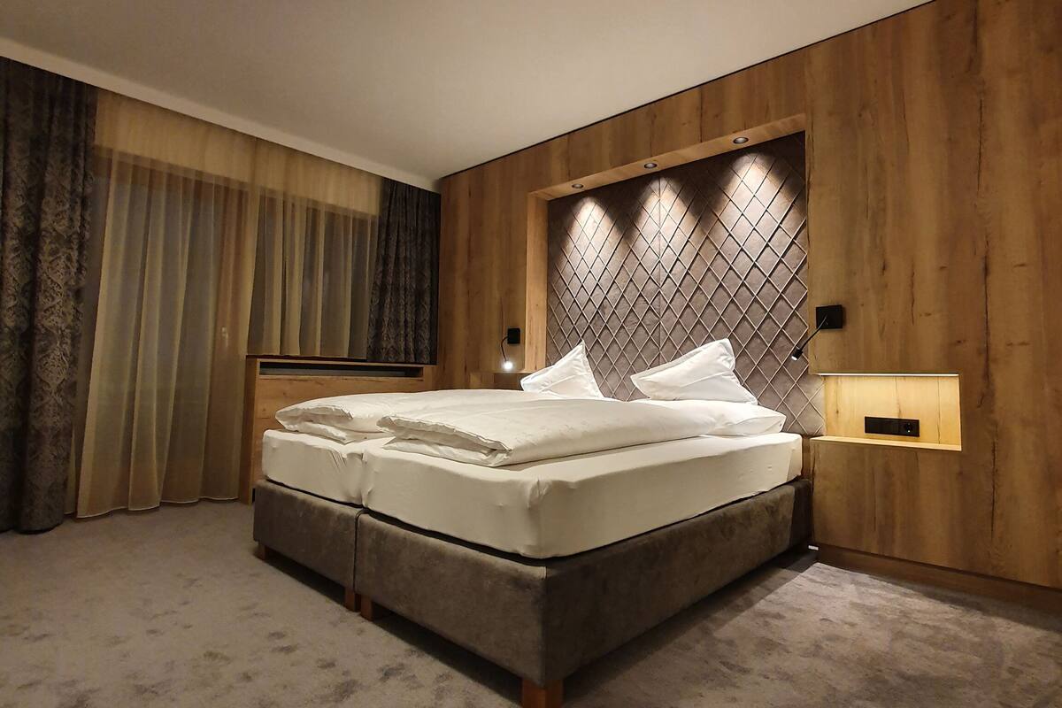 A neatly made bed in a room with wooden paneling and a headboard with a diamond pattern.