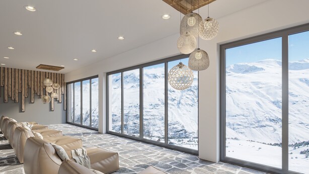 A spacious room with large windows offering a mountain view, stone flooring, and a row of beige sofas. - Alpenhotel Laurin (Soelden)
