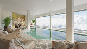 A modern living room with a glass-bottomed pool, a large window with a mountain view, and a cozy seating area with a painting. - Alpenhotel Laurin (Soelden)