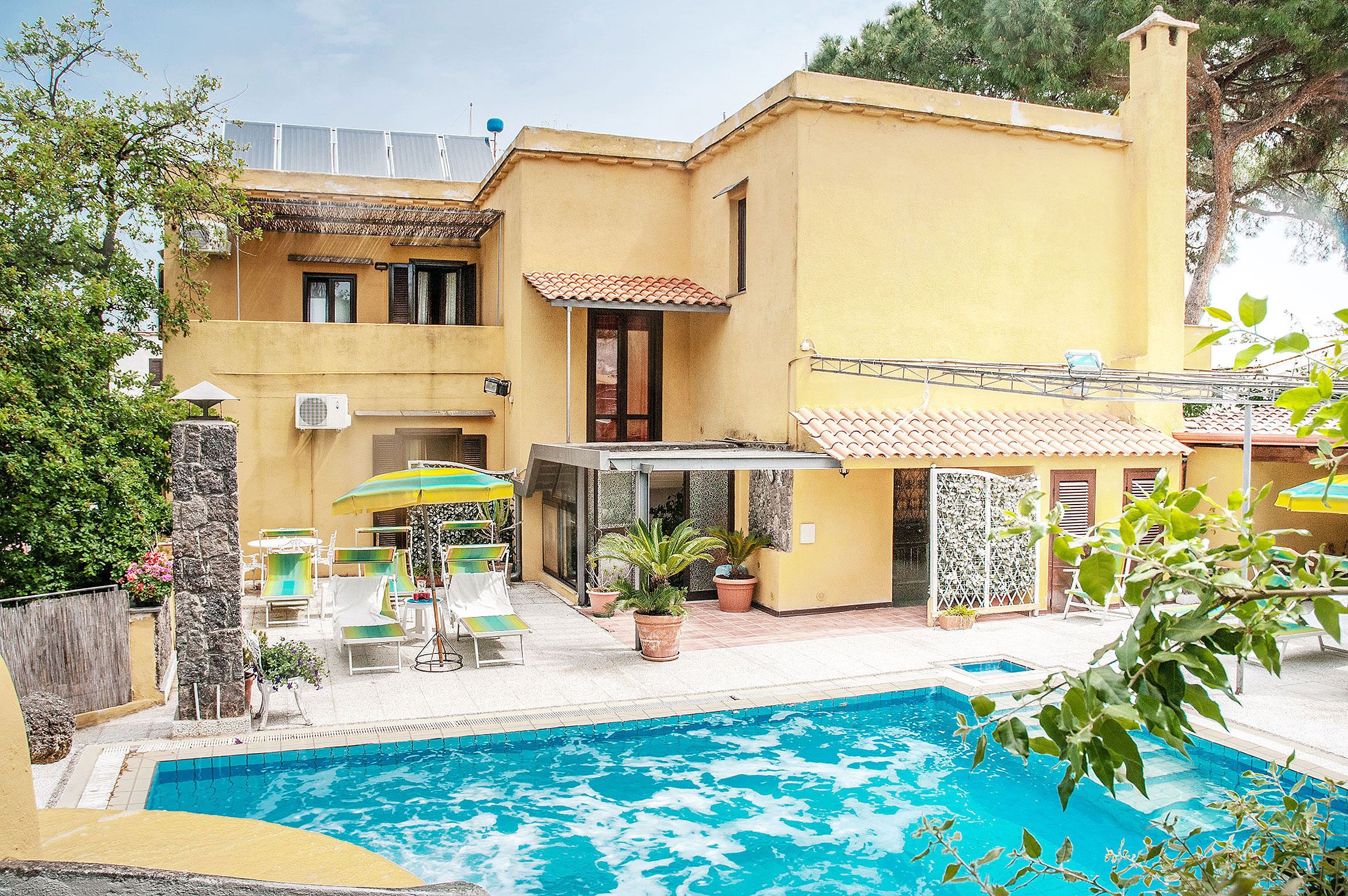 Una propiedad residencial con piscina, mobiliario de exterior y un patio cubierto.