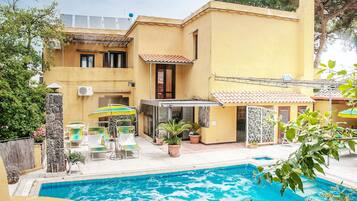 Una propiedad residencial con piscina, mobiliario de exterior y un patio cubierto.