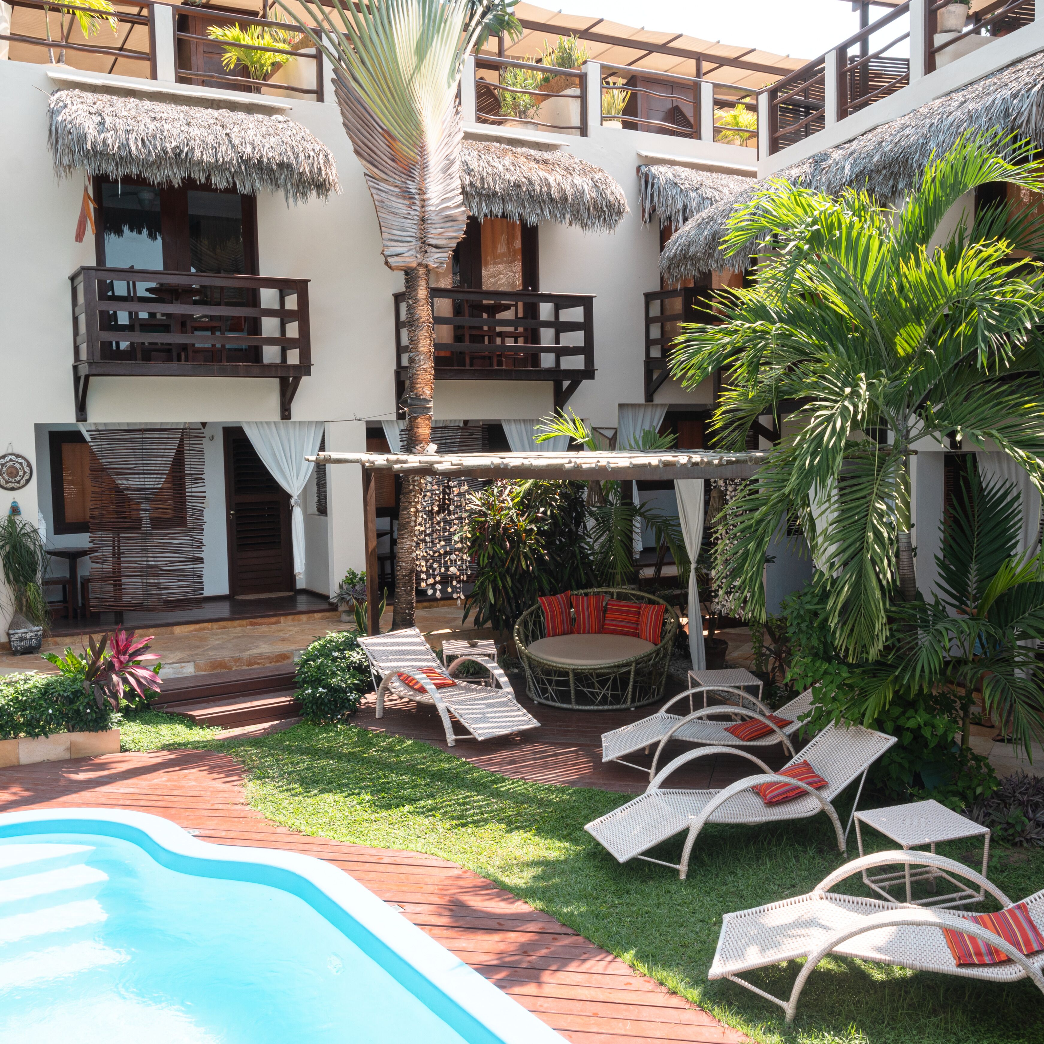 A poolside area with lounge chairs, a small pool, and a thatched-roof structure.