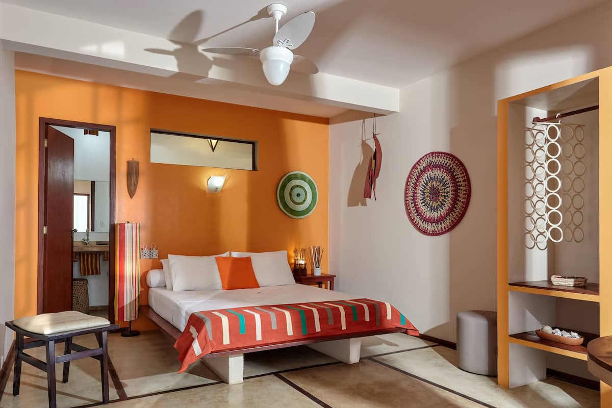 Quarto moderno com cama, mesas de cabeceira, ventilador de teto e parede decorada com pratos.