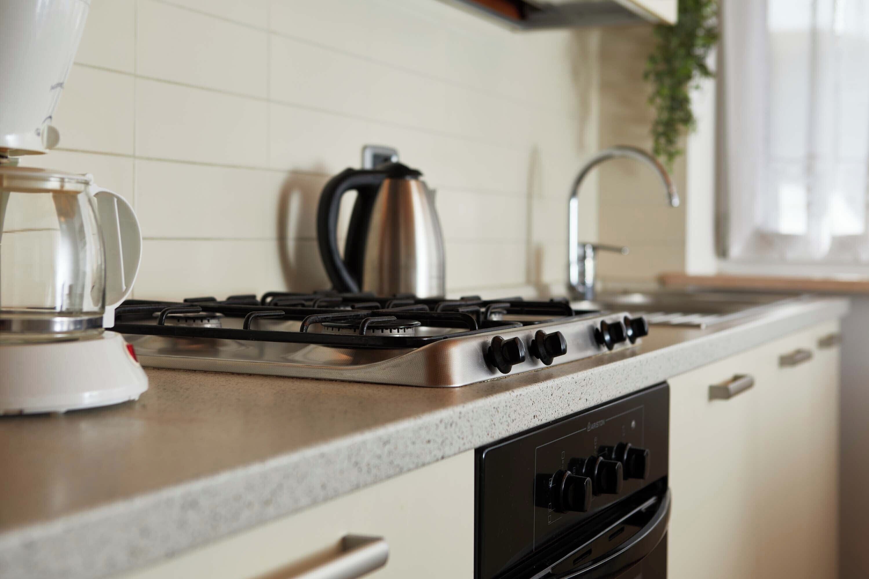 Une cuisine équipée d’une cuisinière à gaz, d’une bouilloire et d’une machine à café.