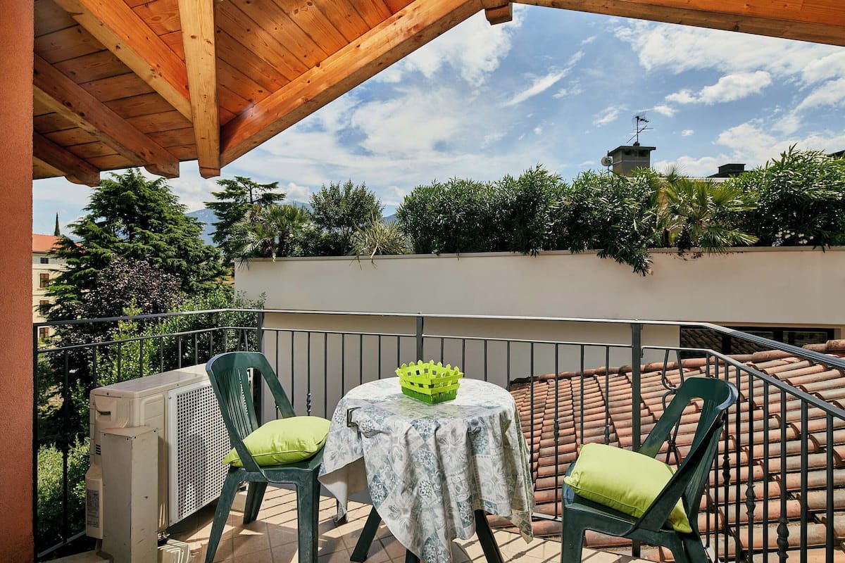 A balcony with a table, chairs, and an air conditioning unit.
