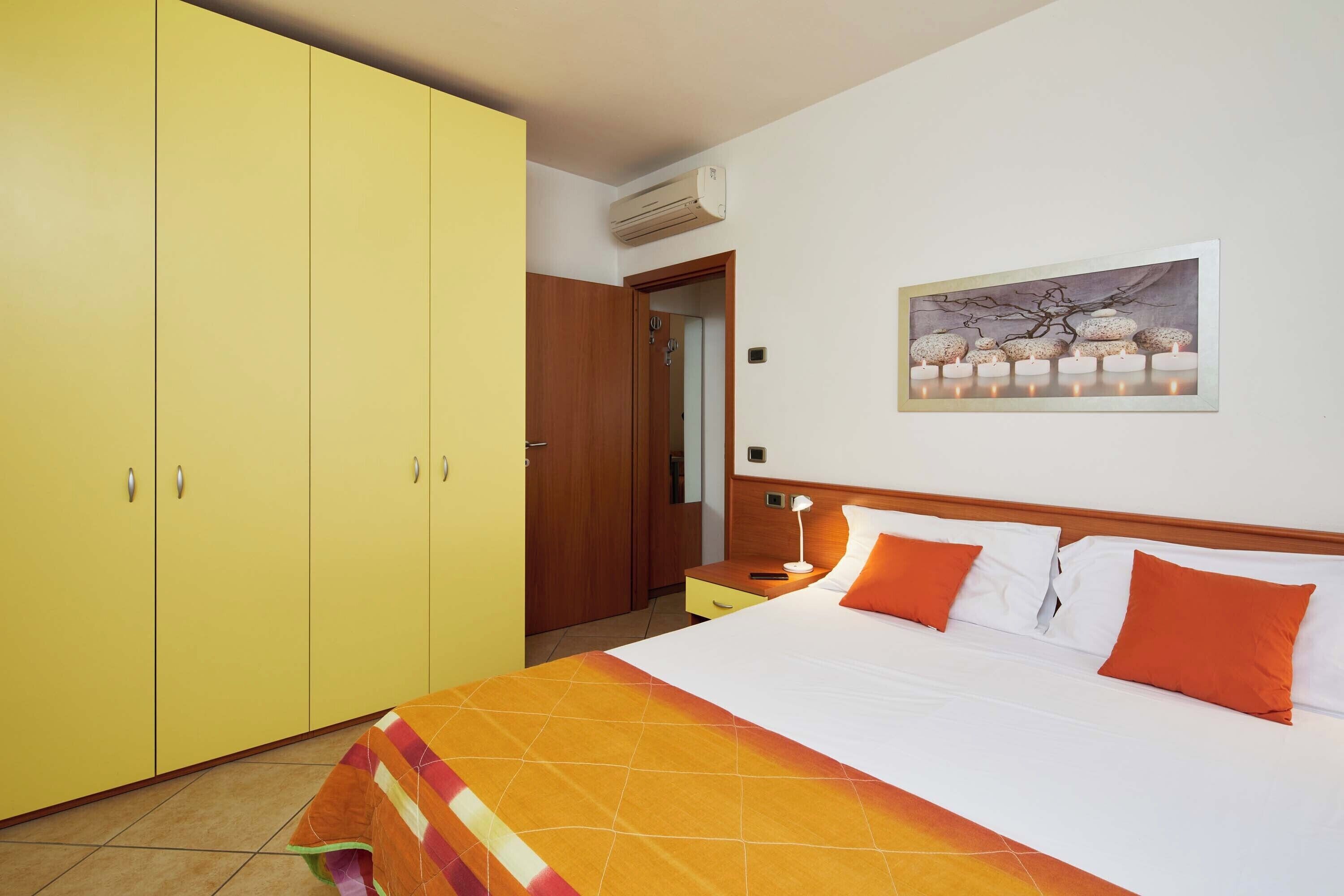 A hotel room with a large bed, a wardrobe, a bedside table, and a painting on the wall.