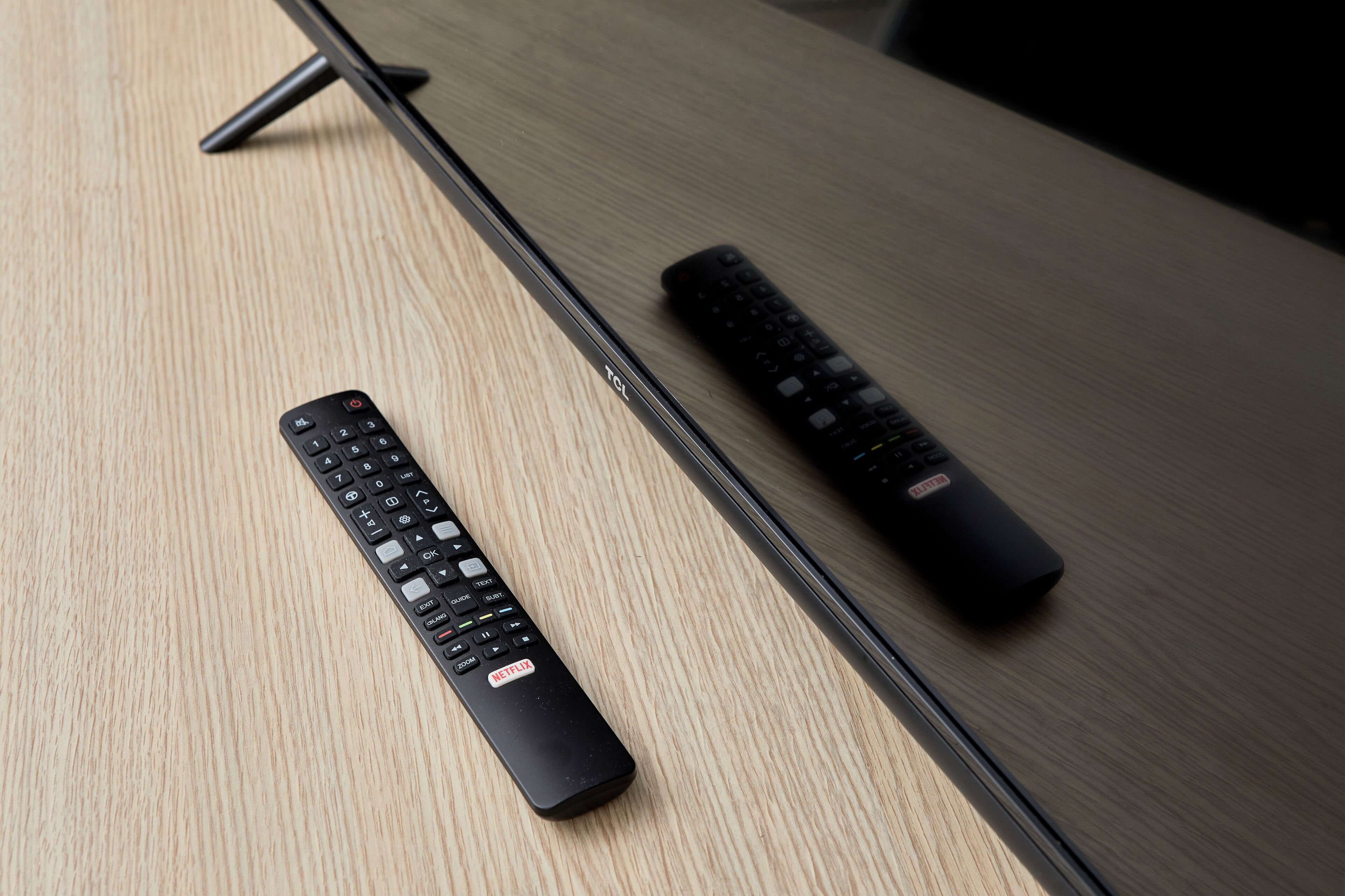 Deux télécommandes posées sur une table en bois.