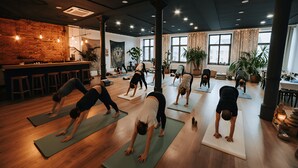 Um estúdio de yoga com pisos de madeira, janelas amplas e plantas em vasos.