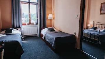 Une chambre d’hôtel avec deux lits simples, une fenêtre avec des rideaux, une lampe sur pied et un radiateur.