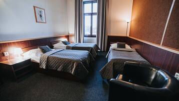 A hotel room with two beds, a desk, a chair, a window with curtains, and a wall-mounted picture.