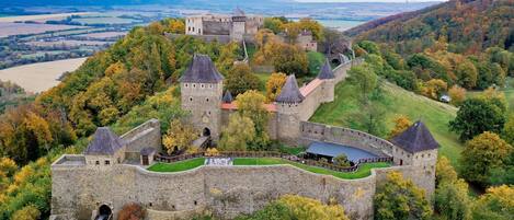 A medieval castle with multiple towers, surrounded by lush autumn foliage.